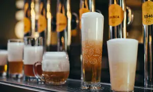 Bicchieri di birra con schiuma abbondante, tra cui una rye ipa decorata con luppoli.
