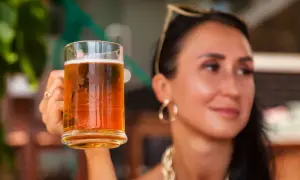 Donna sorridente con in mano un boccale di birra weiss, perfetta per godersi una giornata di sole.