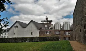 Edificio della Brasserie du Bocq con serbatoi in acciaio inox e un cielo nuvoloso.