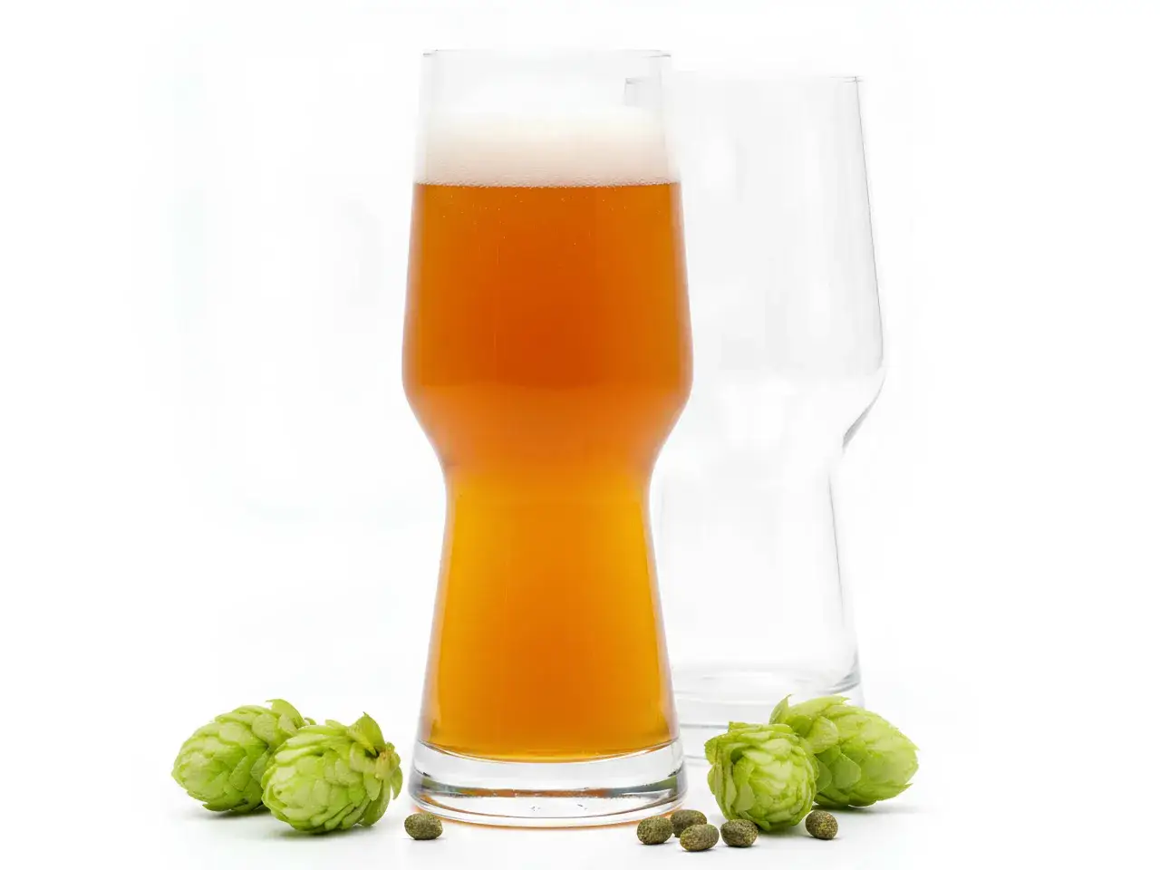 Un bicchiere di birra IPA ambrata con schiuma bianca, circondato da luppoli freschi e pellet. Accanto, un bicchiere vuoto.