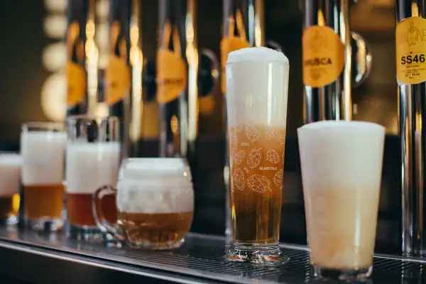Bicchieri di birra con schiuma abbondante, tra cui una rye ipa decorata con luppoli.