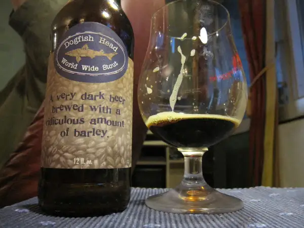 Una bottiglia e un bicchiere di Dogfish Head World Wide Stout, una birra scura con un significato di abbondante orzo.